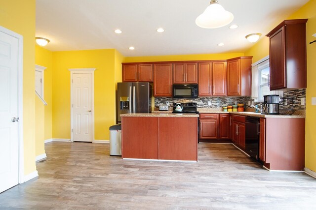 kitchen featuring light hardwood / wood-style flooring, a center island, decorative backsplash, and black appliances