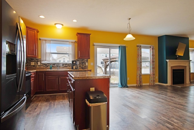 kitchen with stainless steel refrigerator with ice dispenser, a kitchen island, plenty of natural light, and decorative backsplash