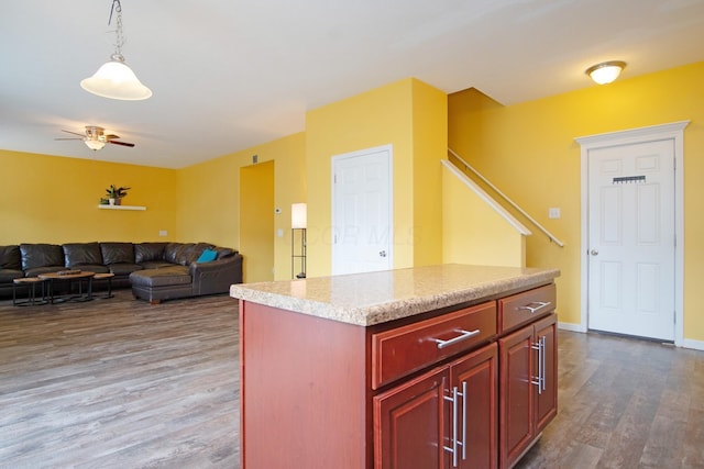 kitchen featuring ceiling fan, wood-type flooring, decorative light fixtures, and a kitchen island