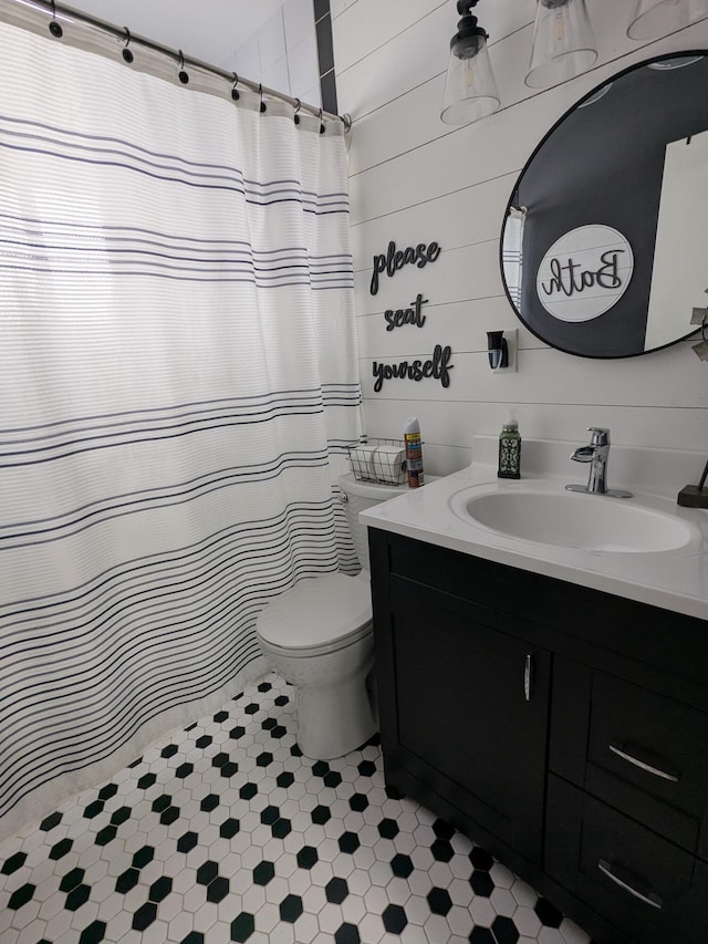 bathroom with vanity, a shower with curtain, toilet, and wooden walls