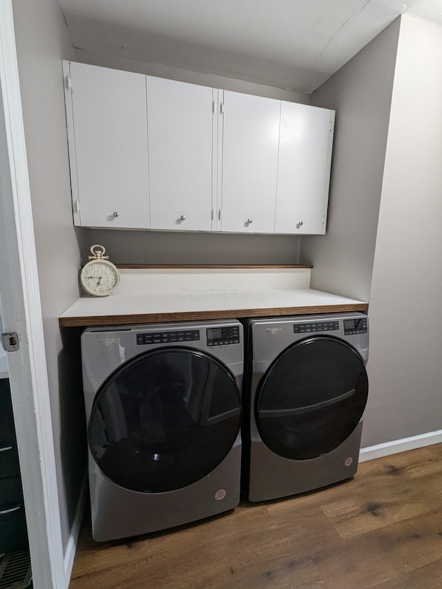 clothes washing area with cabinets, dark wood-type flooring, and separate washer and dryer