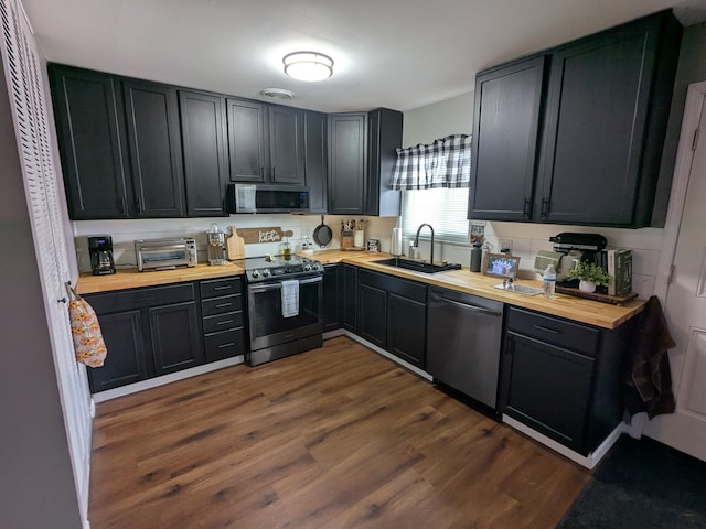 kitchen featuring wooden counters, appliances with stainless steel finishes, sink, and dark hardwood / wood-style floors