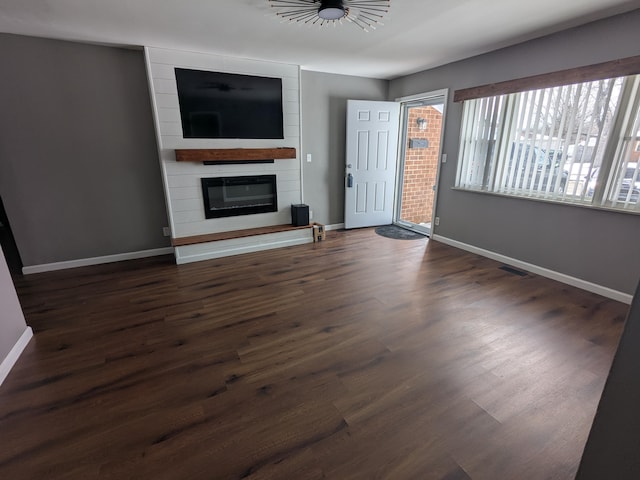 unfurnished living room with dark wood-type flooring and a fireplace