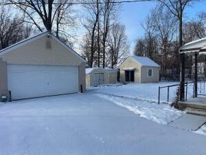 yard layered in snow featuring a garage and an outdoor structure