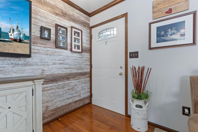 entrance foyer with crown molding, hardwood / wood-style floors, and wood walls