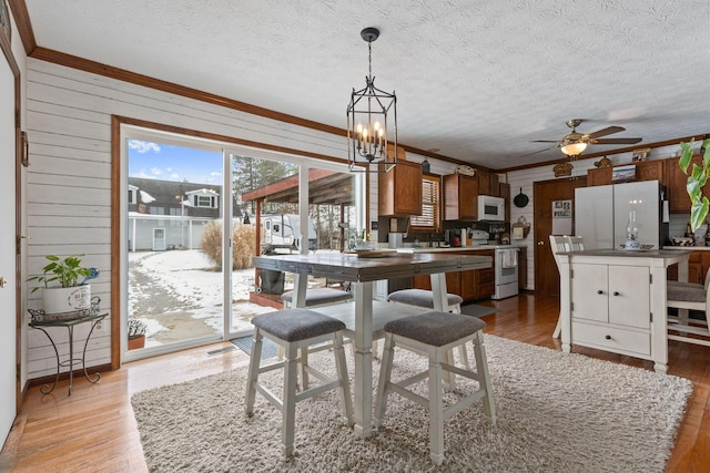 dining area featuring ornamental molding, a textured ceiling, and light hardwood / wood-style floors