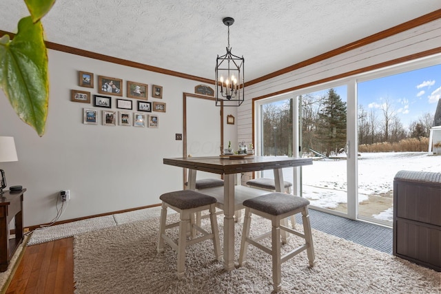 dining space with a healthy amount of sunlight, hardwood / wood-style floors, a textured ceiling, and a notable chandelier