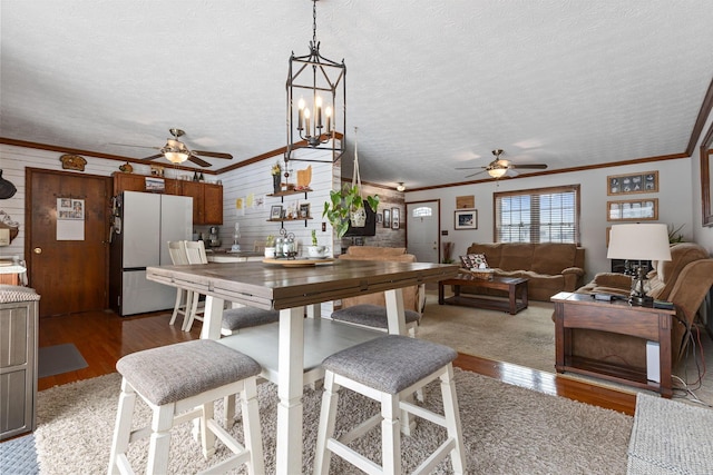 dining area featuring hardwood / wood-style flooring, ornamental molding, a textured ceiling, and wood walls