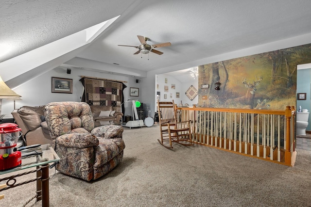 living room featuring ceiling fan, carpet flooring, vaulted ceiling with skylight, and a textured ceiling