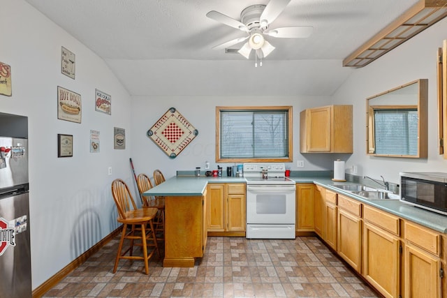 kitchen with sink, stainless steel refrigerator, a kitchen breakfast bar, kitchen peninsula, and electric stove