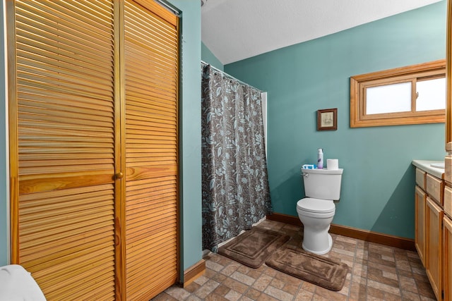 bathroom featuring lofted ceiling, toilet, and vanity