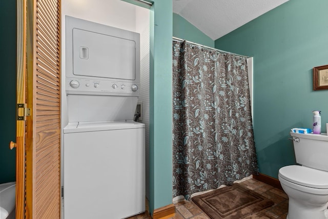 bathroom with vaulted ceiling, stacked washer and dryer, toilet, a textured ceiling, and a shower with shower curtain