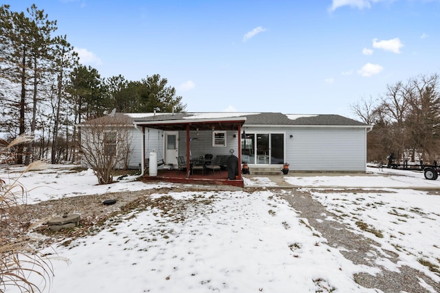 snow covered back of property featuring a porch