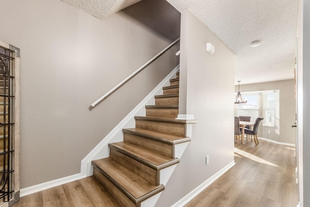 staircase featuring hardwood / wood-style flooring and a textured ceiling