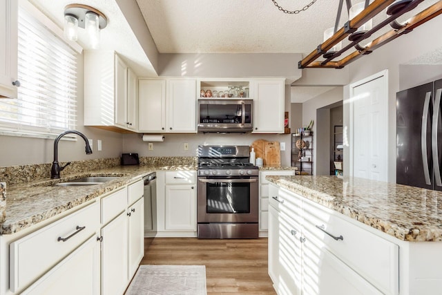 kitchen featuring stainless steel appliances, light stone countertops, sink, and white cabinets