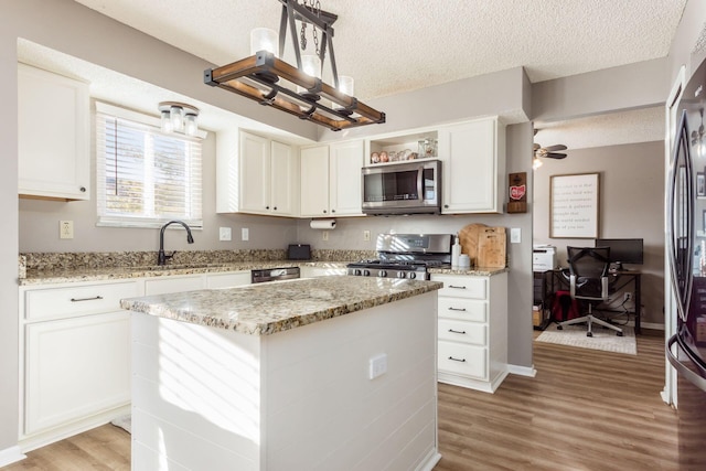 kitchen featuring appliances with stainless steel finishes, a center island, light stone counters, a textured ceiling, and white cabinets