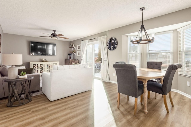 living room with ceiling fan with notable chandelier, wood-type flooring, and a textured ceiling