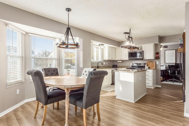 dining room with sink, a notable chandelier, a textured ceiling, and light hardwood / wood-style flooring