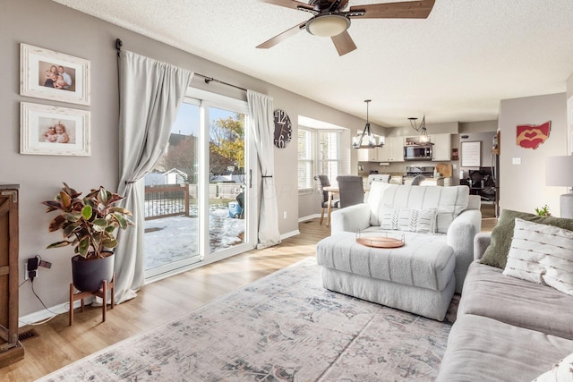 living room featuring ceiling fan, a textured ceiling, and light wood-type flooring