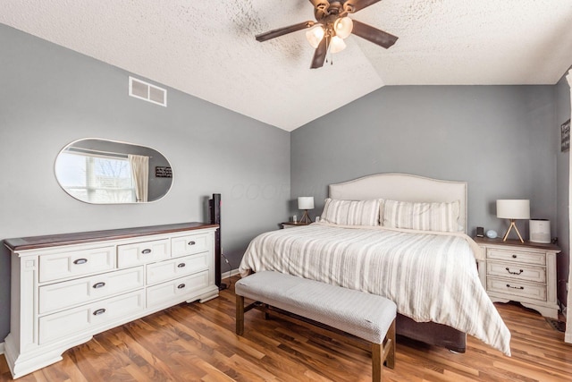 bedroom with lofted ceiling, hardwood / wood-style flooring, a textured ceiling, and ceiling fan