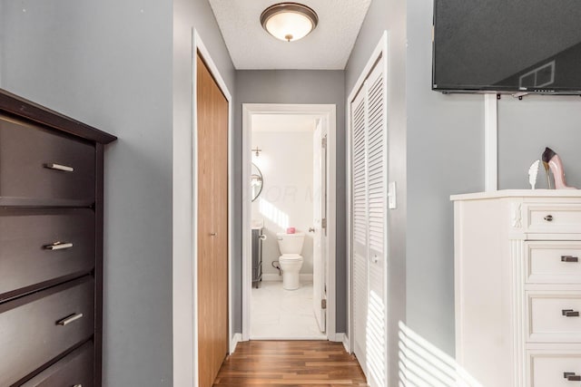 corridor with wood-type flooring and a textured ceiling