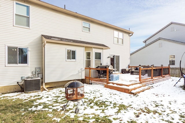 snow covered house with cooling unit, a fire pit, and a deck