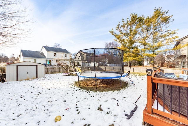 snowy yard with a trampoline and a shed