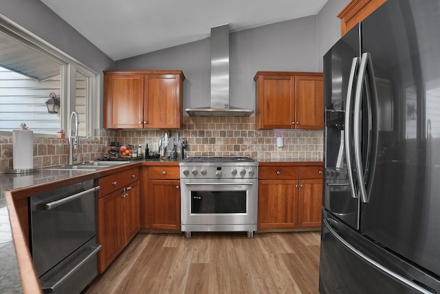 kitchen with lofted ceiling, wall chimney range hood, sink, stainless steel appliances, and light wood-type flooring