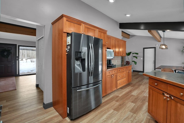 kitchen featuring decorative light fixtures, dark countertops, white microwave, brown cabinetry, and refrigerator with ice dispenser