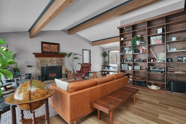 living room featuring lofted ceiling with beams, light wood-style flooring, a fireplace, and a chandelier