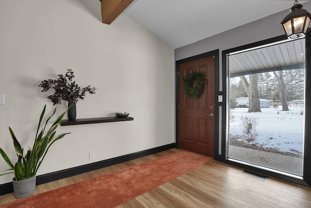 entryway featuring lofted ceiling with beams, wood finished floors, visible vents, and baseboards