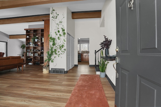 entryway featuring beam ceiling, visible vents, wood finished floors, baseboards, and stairs