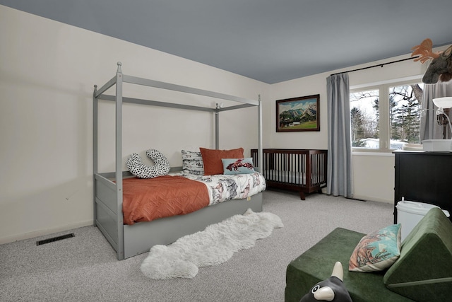 bedroom with baseboards, visible vents, and light colored carpet