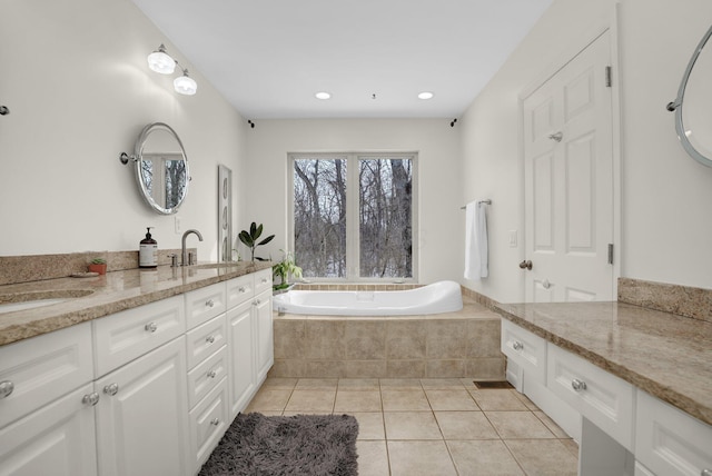 bathroom featuring a relaxing tiled tub, vanity, and tile patterned flooring