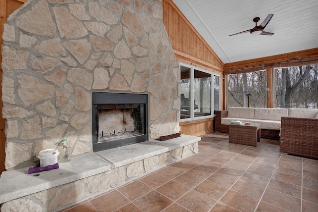 unfurnished sunroom featuring vaulted ceiling, ceiling fan, a stone fireplace, and wood ceiling