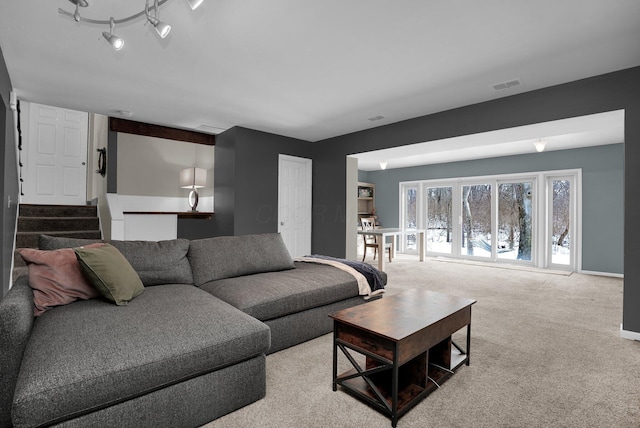 living room with stairway, light colored carpet, visible vents, and baseboards