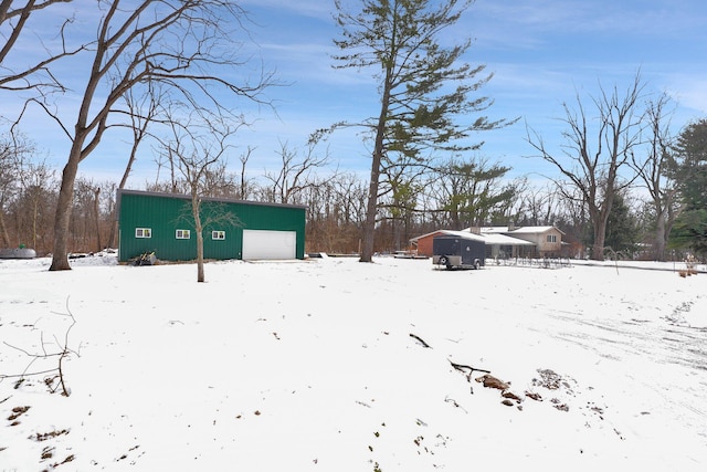 yard layered in snow with a garage and an outdoor structure