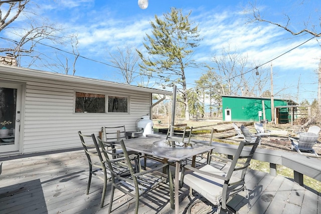 wooden terrace featuring outdoor dining area and an outdoor structure