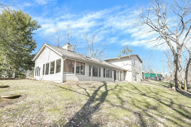 exterior space with a yard, a chimney, an attached garage, and a sunroom