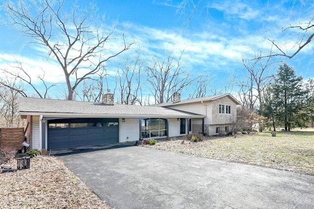 tri-level home featuring aphalt driveway, roof with shingles, a chimney, and an attached garage