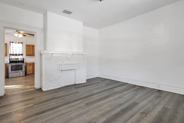 unfurnished living room featuring dark wood-type flooring, ceiling fan, and a fireplace