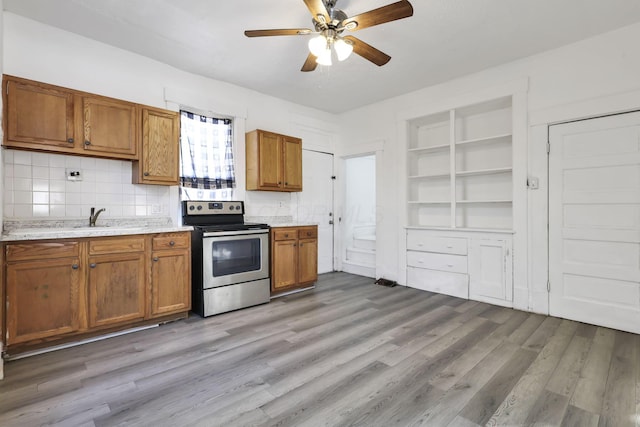 kitchen featuring built in features, ceiling fan, electric range, tasteful backsplash, and light wood-type flooring