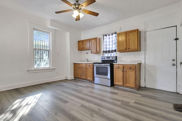 kitchen with stainless steel electric range oven, backsplash, ceiling fan, and light hardwood / wood-style flooring