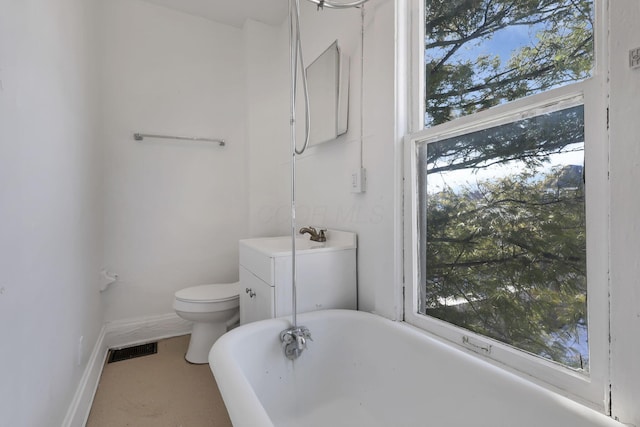 bathroom with toilet, vanity, and a tub to relax in