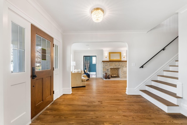 entrance foyer featuring ornamental molding, wood-type flooring, and a fireplace