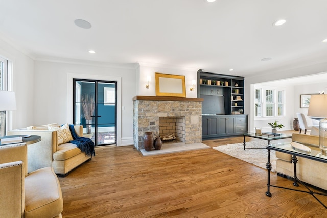 living room featuring hardwood / wood-style flooring, crown molding, plenty of natural light, and a fireplace