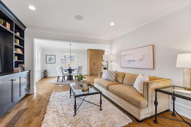 living room featuring ornamental molding, a notable chandelier, and light hardwood / wood-style flooring