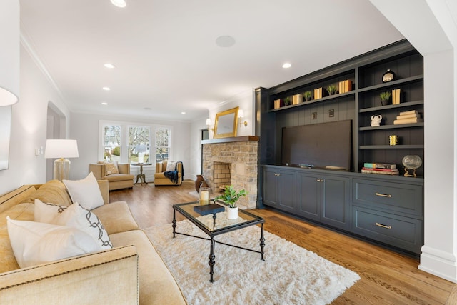 living room with ornamental molding, built in features, and light hardwood / wood-style flooring