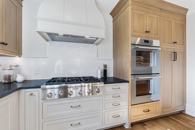 kitchen with appliances with stainless steel finishes, decorative backsplash, light hardwood / wood-style floors, custom range hood, and light brown cabinets