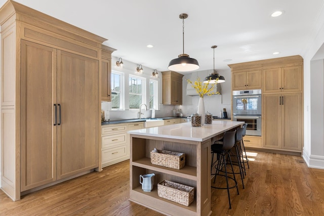 kitchen with light hardwood / wood-style floors, decorative light fixtures, a center island, and double oven